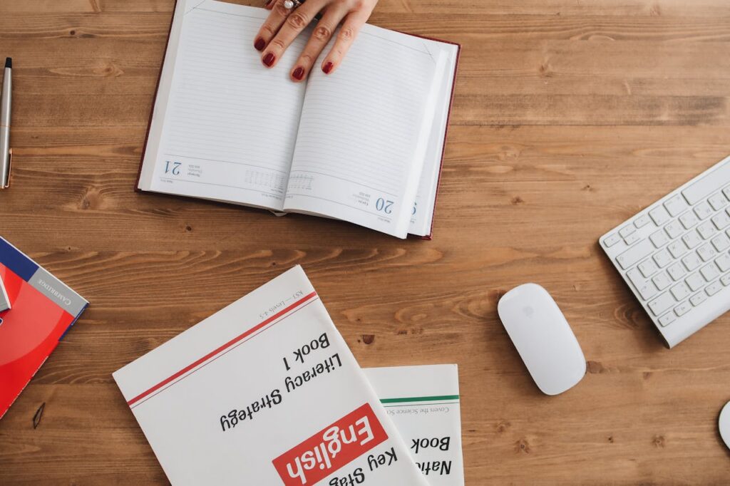 Open planner and English workbooks on a wooden desk, ideal for study-themed visuals.